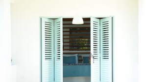 Quarto com guarda-roupa com portadas azuis claras, cama com colcha azul e luminária suspensa.