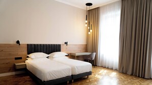 Quarto de hotel moderno com uma cama grande, uma escrivaninha e uma cadeira.
