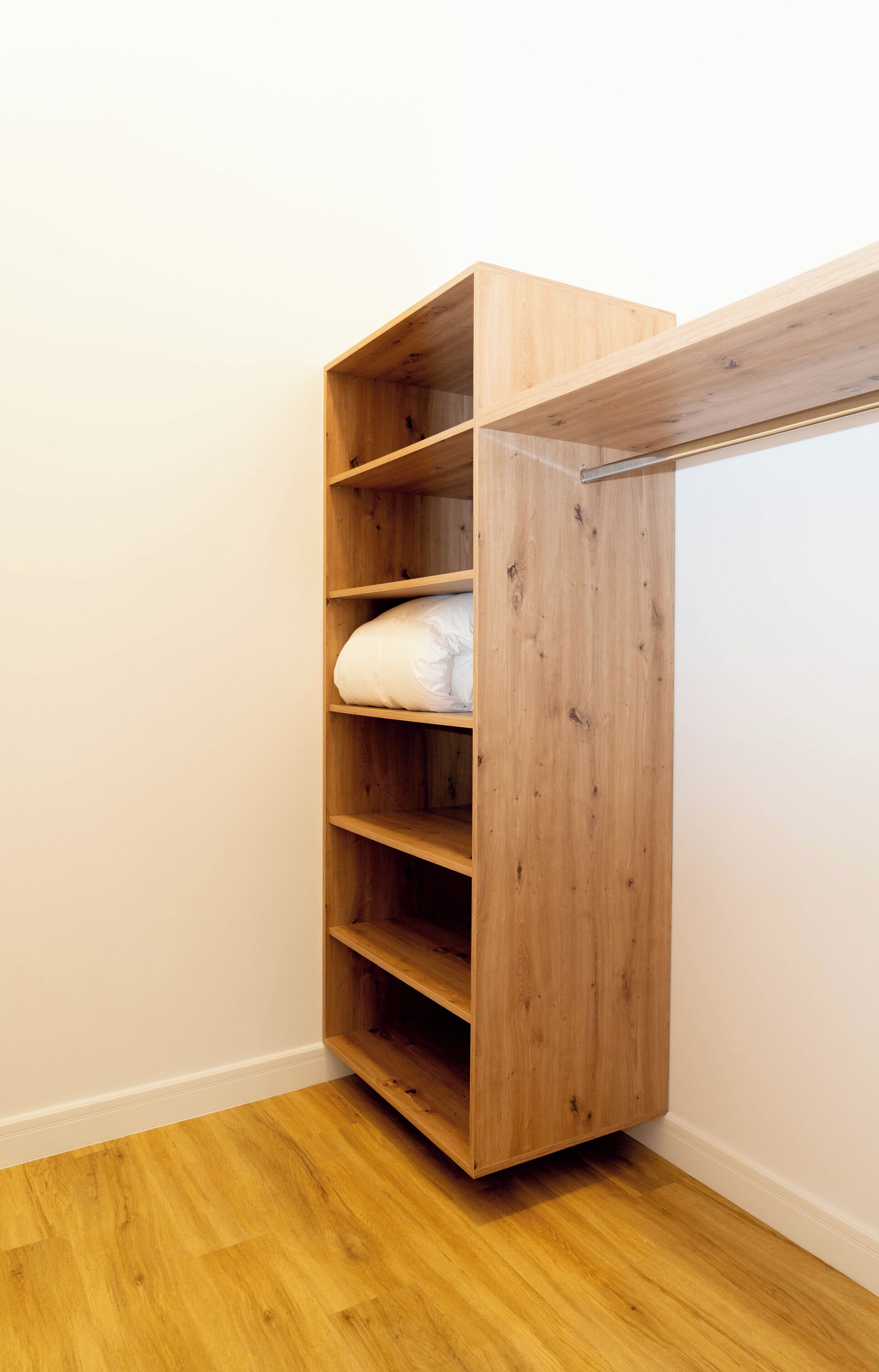 A wooden closet with multiple shelves and a hanging rod.