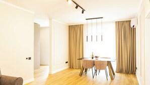 Uma zona de refeições moderna com chão de madeira, uma mesa redonda e duas cadeiras.