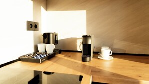 Uma cozinha moderna com cafeteira, chaleira e xícaras sobre uma mesa de madeira.
