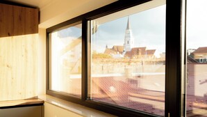 Janela com vista para um campanário de igreja e edifícios.