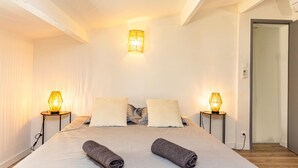 A bedroom with a large bed, two bedside lamps, and a door to another room. - Charming  Townhouse Mon voisin Van Gogh (Arles)
