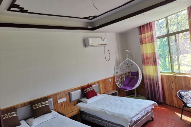 A hotel room with two beds, a hanging chair, and a window with curtains.