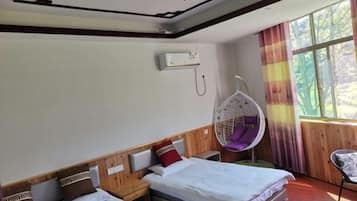 A hotel room with two beds, a hanging chair, and a window with curtains.