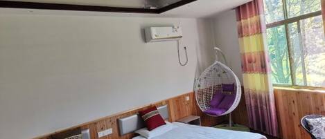 A hotel room with two beds, a hanging chair, and a window with curtains.