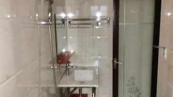 A bathroom with a glass shower enclosure, a towel rack, and a door with a decorative pattern.
