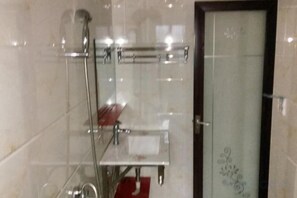 A bathroom with a glass shower enclosure, a towel rack, and a door with a decorative pattern. - nqkz (Wuyuan)