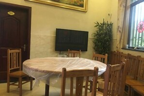 A room with a round table covered with a plastic sheet, surrounded by wooden chairs, a television on the wall, and a door marked with the number 101. - nqkz (Wuyuan)