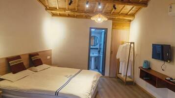 A bedroom with a wooden ceiling, a bed with a headboard, a mirror, a television, and a small shelf.