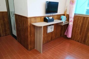 A small room with a television, a shelf with a kettle, and a window with a curtain. - nqkz (Wuyuan)