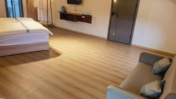 Een hotelkamer met een bed, een slaapbank, een televisie aan de muur en een kledingrek.
