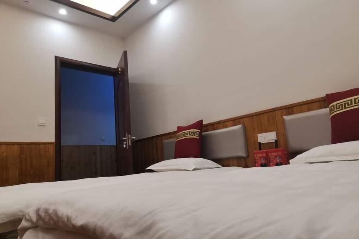 A hotel room with a bed, a wooden headboard, a door, and a wall-mounted light fixture.