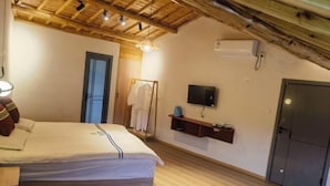 Un dormitorio con cama, techo de madera, televisor montado en la pared, armario y una puerta.