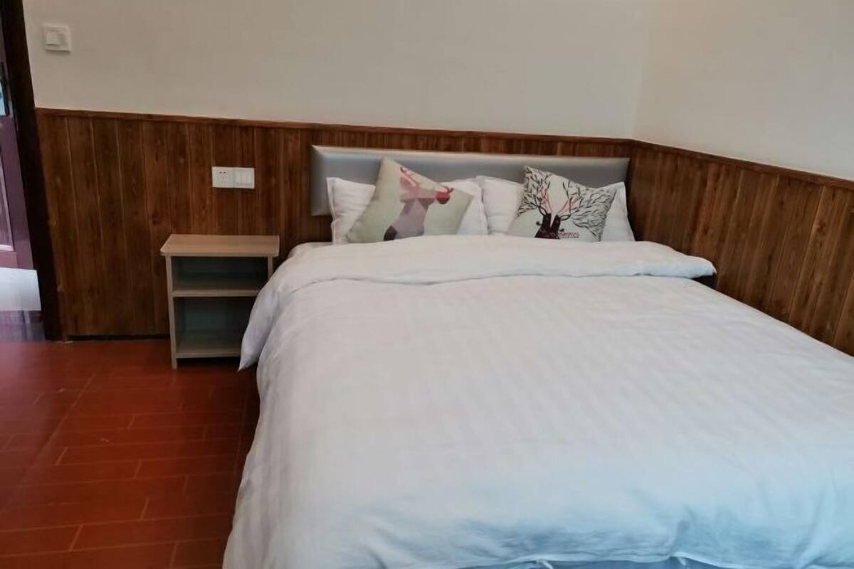 A hotel room with a wooden headboard, a bed with white bedding, and a small bedside table.