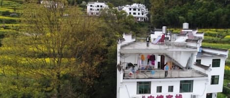 Un immeuble à plusieurs étages doté de balcons, entouré de verdure et de collines.