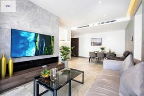 Relax in this stylish living room with a large flat-screen TV, comfortable sofa, and dining area.