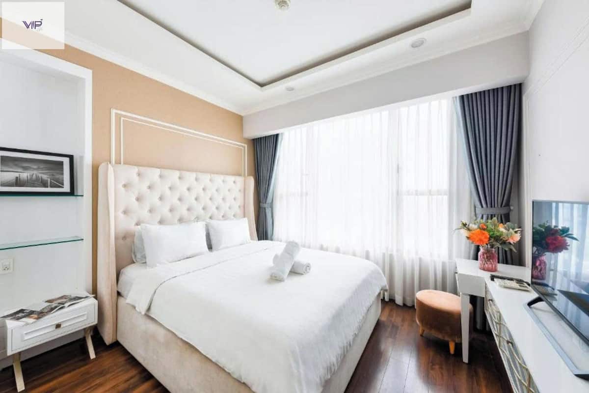 A hotel room with a large bed, a desk, a chair, and a TV.