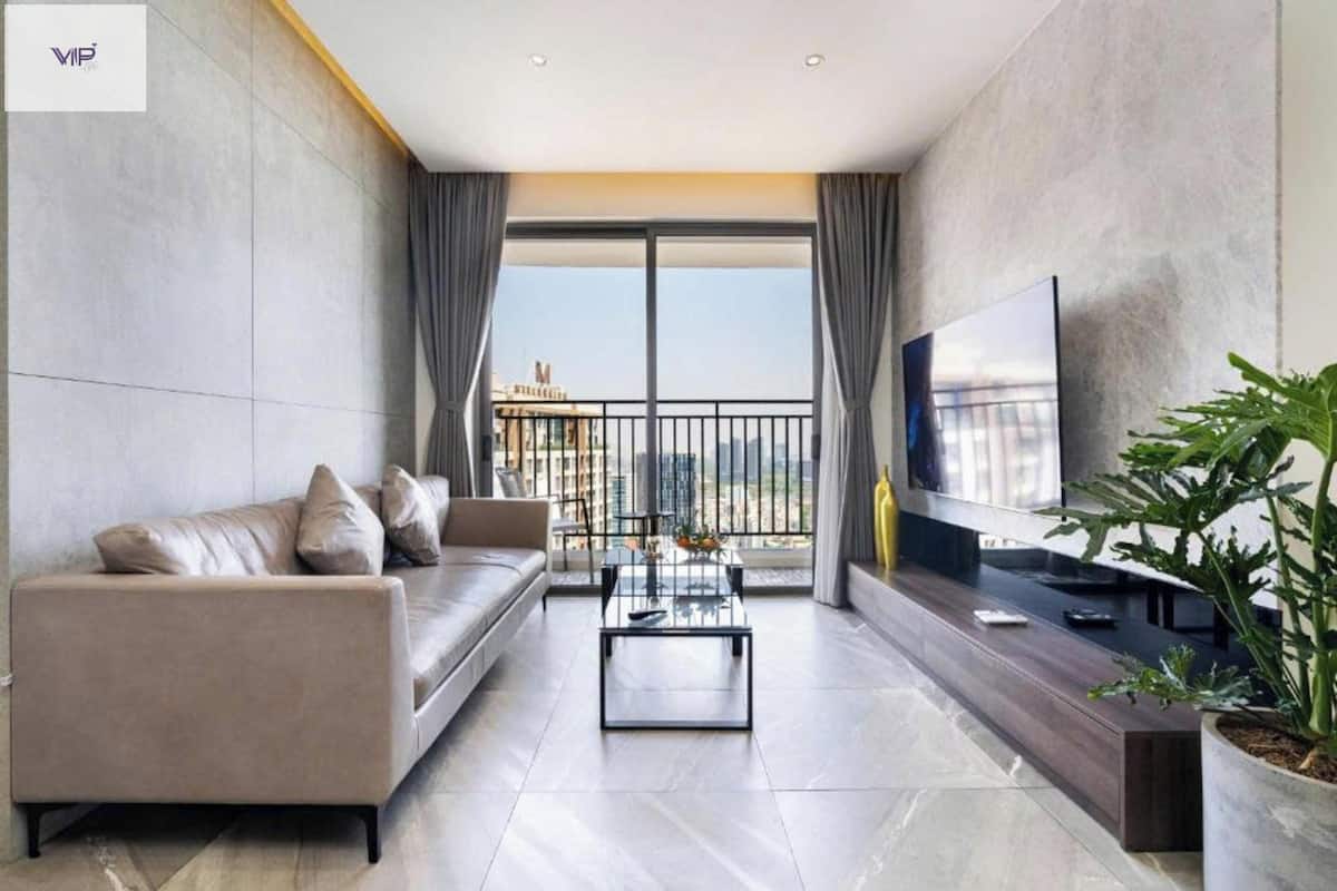 A modern living room with a sofa, a coffee table, a TV, and a balcony with a city view.