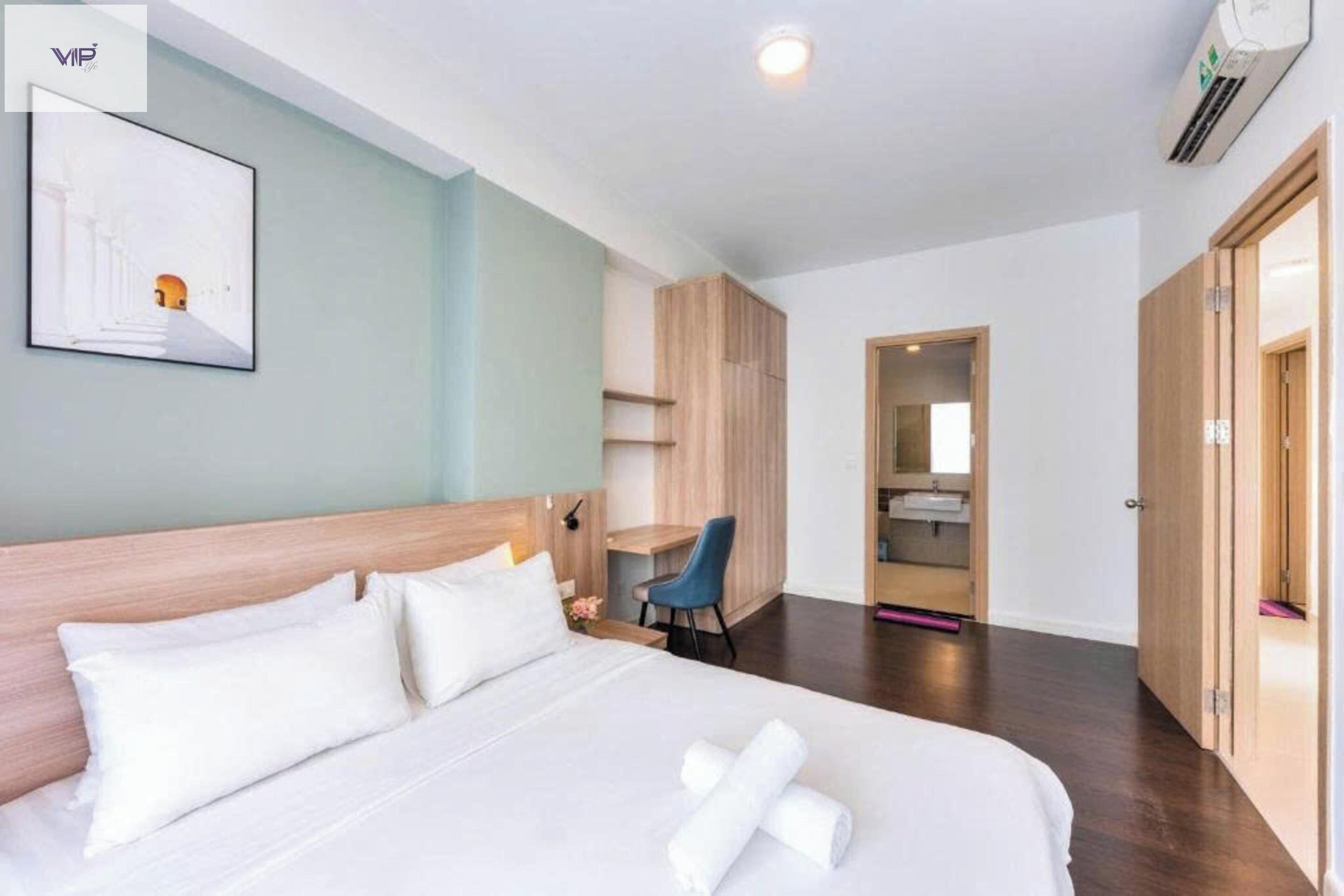 Ein Hotelzimmer mit Bett, Schreibtisch, Stuhl, Kleiderschrank und einem durchgegangenen Tür sichtbaren Badezimmer.