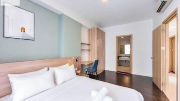 Ein Hotelzimmer mit Bett, Schreibtisch, Stuhl, Kleiderschrank und einem durchgegangenen Tür sichtbaren Badezimmer.