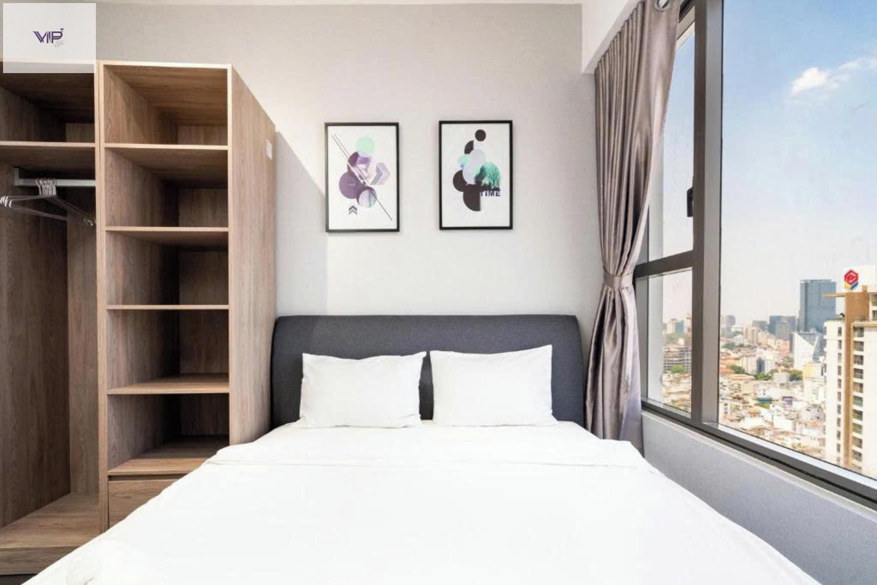Ein modernes Hotelzimmer mit einem großen Bett, einem Holzschrank und zwei gerahmten Kunstwerken an der Wand.