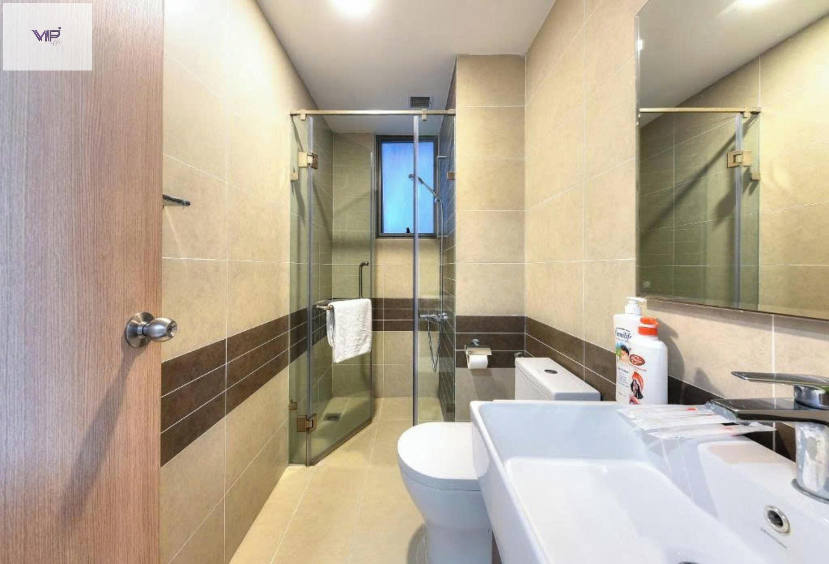 Un baño moderno con ducha de vidrio, inodoro blanco y un lavamanos grande y blanco.