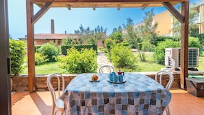 An outdoor patio with a table set for two, surrounded by a wooden pergola. - Dimora Oleandro 50mt From Beach (Stintino)