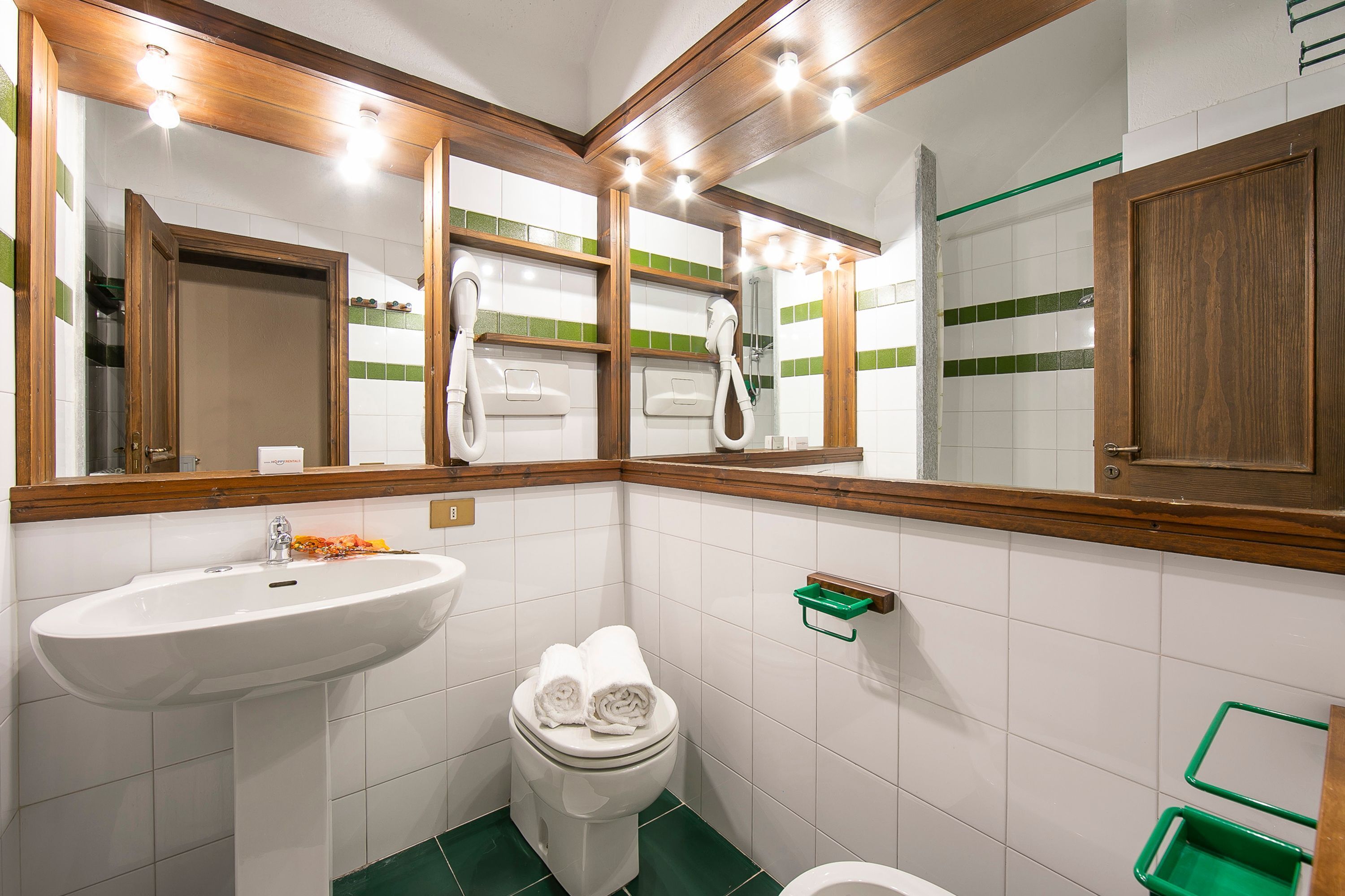 A bathroom with a white sink, a toilet, and a mirror with wooden frames.
