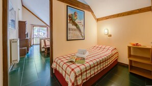 Une chambre avec un lit, une affiche accrochée au mur, une étagère en bois et une vue sur l’extérieur.