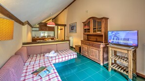 Un salon chaleureux avec un canapé à carreaux, un meuble en bois et un téléviseur posé sur un support en bois.