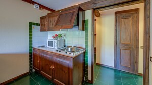 A compact kitchen with wooden cabinets, a microwave, and a stove.