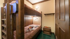 A compact room with a bunk bed, a small bedside table, and a nightstand.