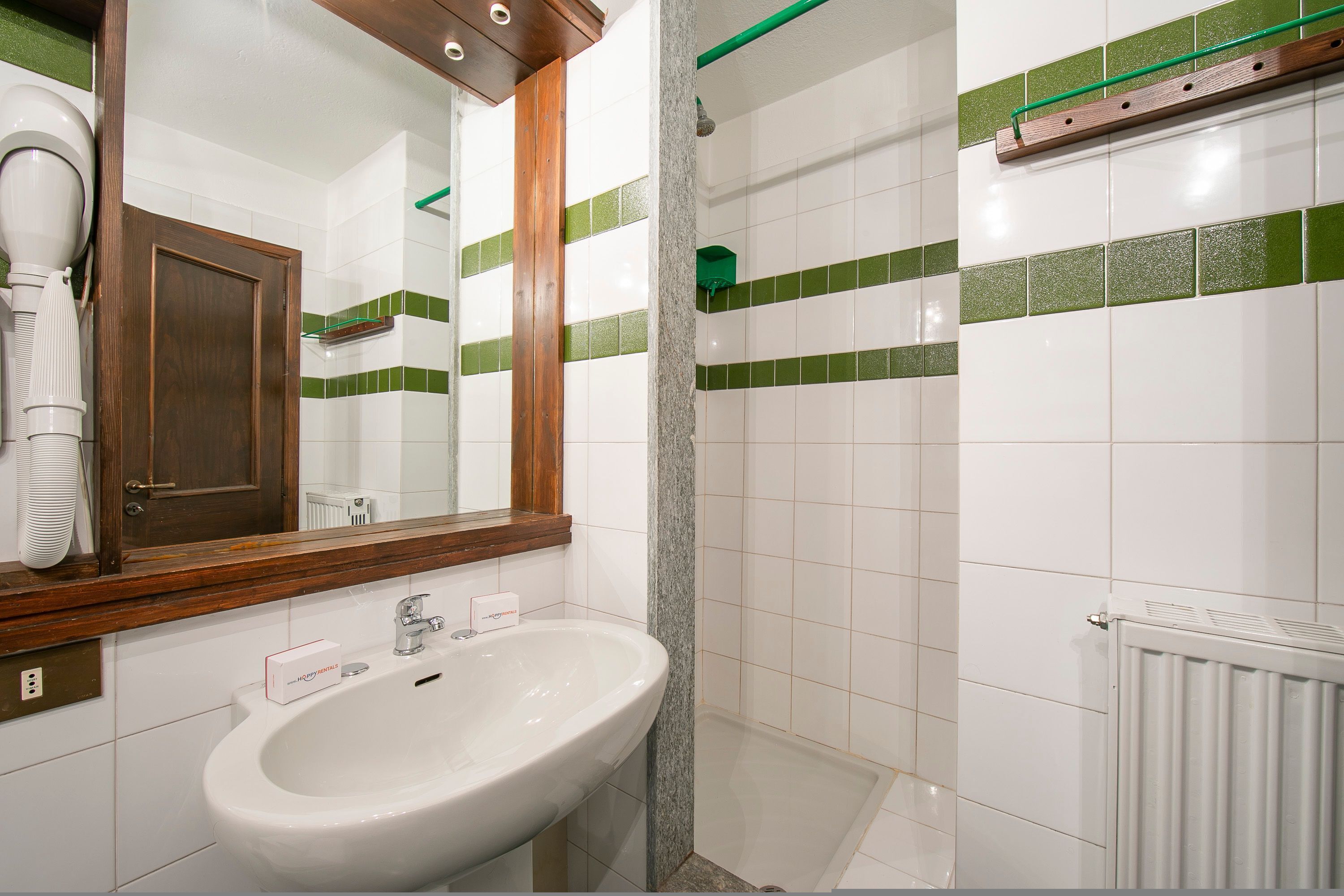 A bathroom with a white sink, a mirror, and green-tiled walls.