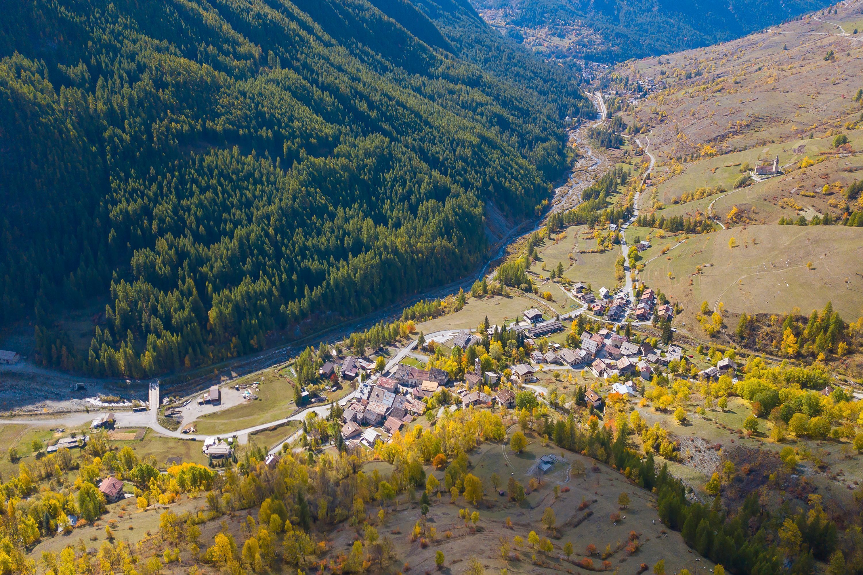 Un pueblo enclavado en un valle, con un río que lo atraviesa, rodeado de colinas boscosas.