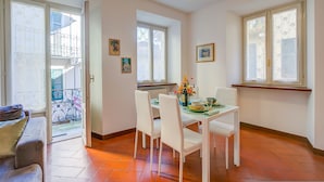 A dining area with a table set for four, chairs, and a vase of flowers.
