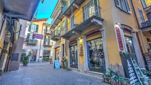 A narrow street with shops on either side, including a visible sign for a restaurant and a boutique.