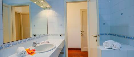 A bathroom with a white sink, a mirror, and a shower area.