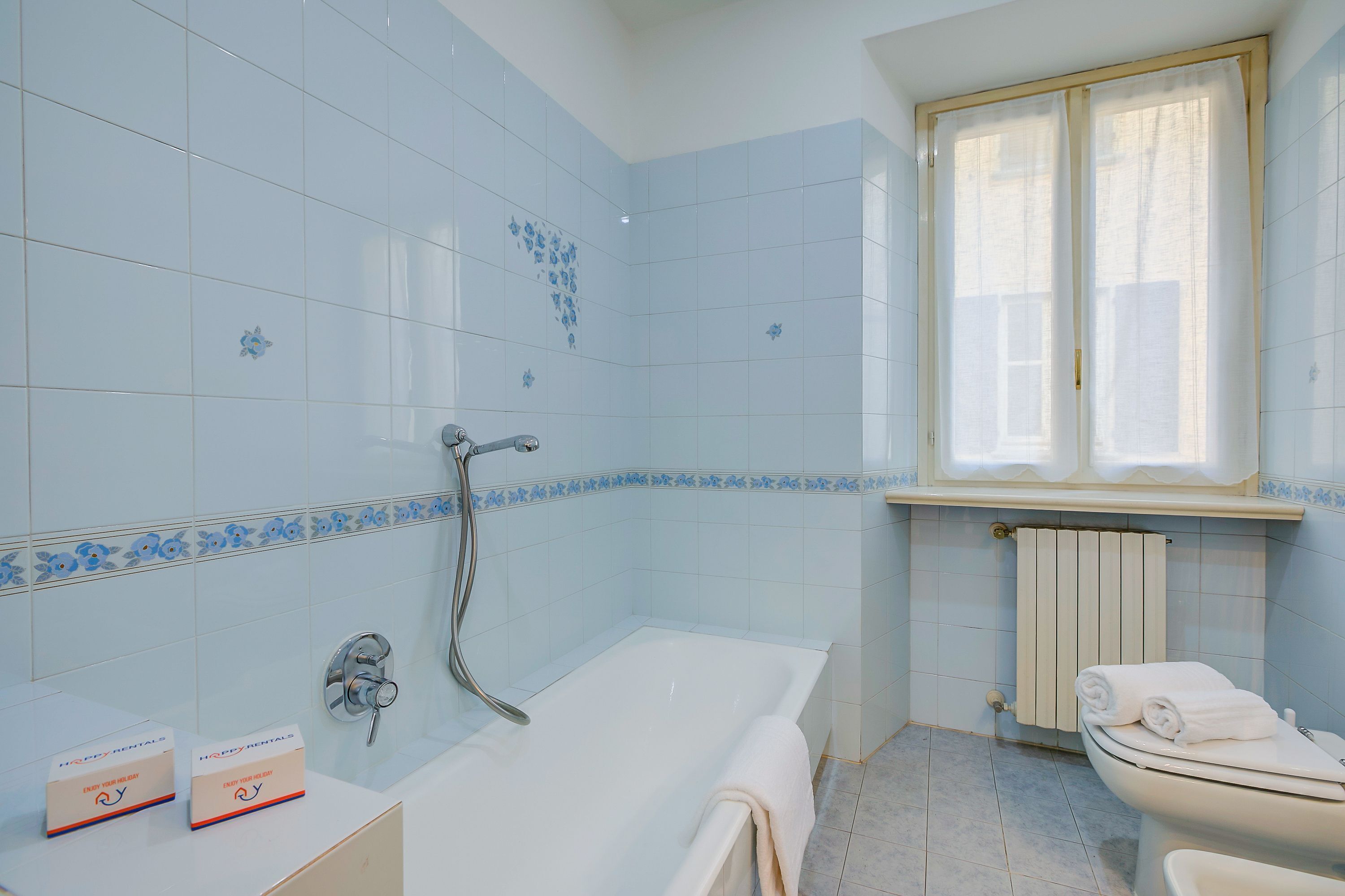 Un baño con bañera, inodoro y ventana.