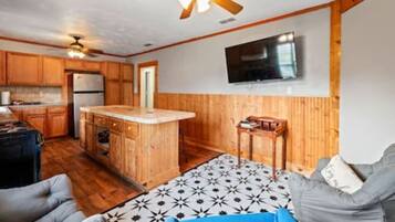 A compact kitchen with wooden cabinets, a central island, and a ceiling fan.