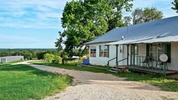 A single-story house with a porch, a gravel driveway, and a grassy yard.