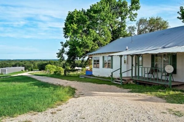 A single-story house with a porch, a gravel driveway, and a grassy yard.