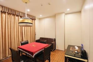 A hotel room with a dining table, chairs, a small table with a lamp, and a curtain. - Xinghe Business Hotel (Luhe)