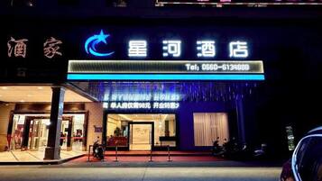 A hotel entrance with a sign displaying the name and contact number.