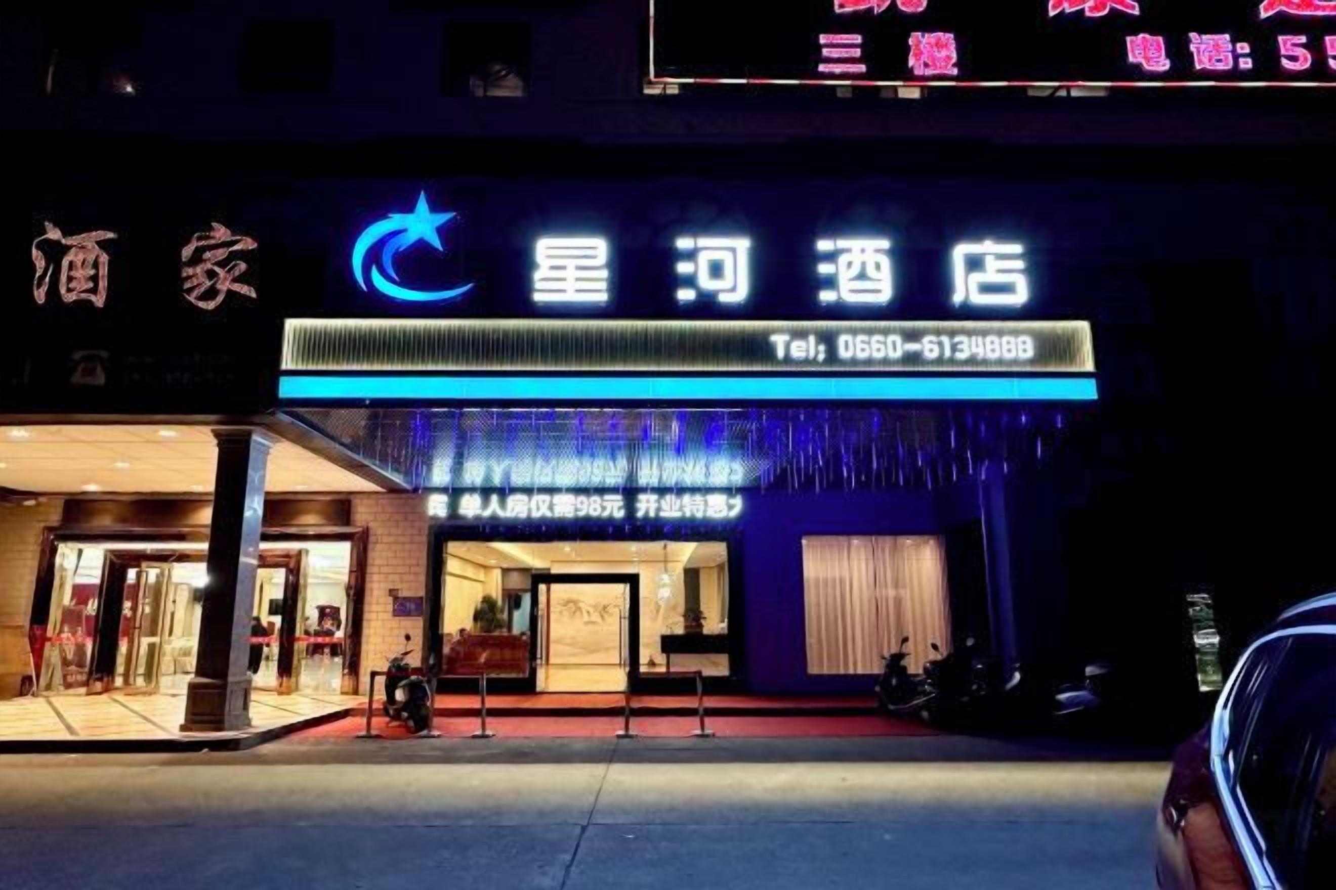 A hotel with a prominent sign displaying the name and contact number.