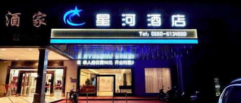 A hotel with a prominent sign displaying the name and contact number.