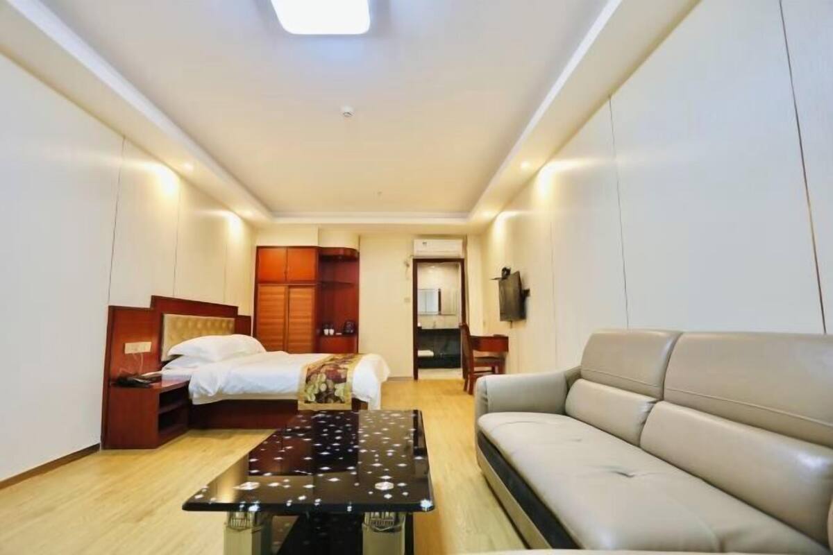A hotel room with a bed, a sofa, a small table, and a wardrobe.
