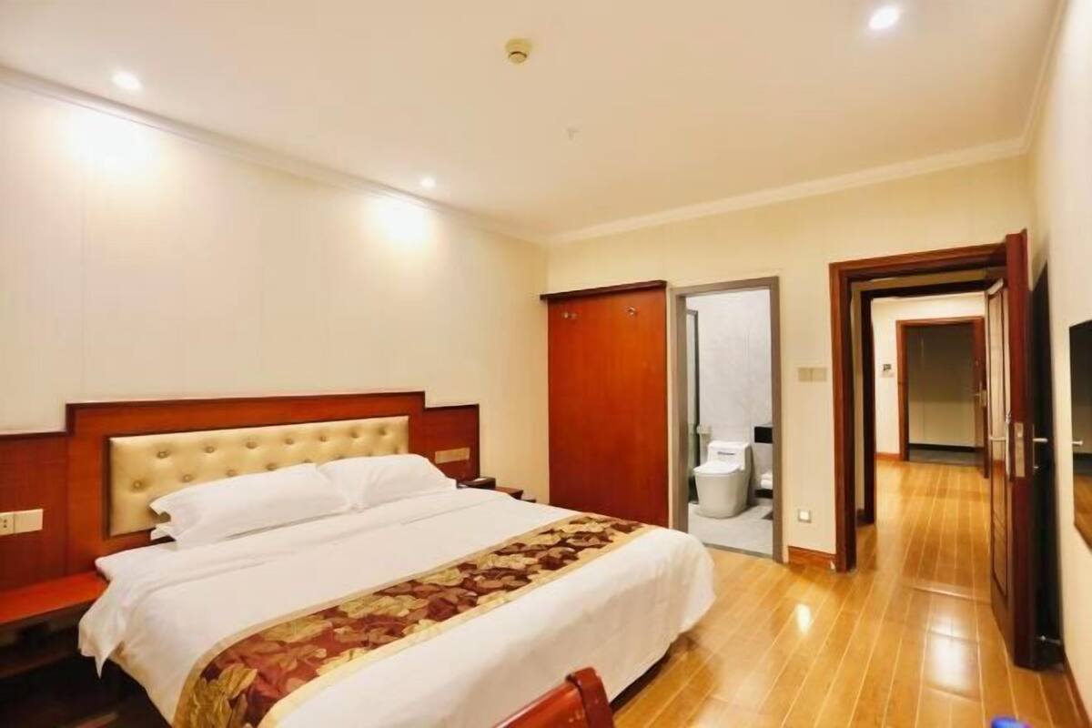 A hotel room with a large bed, wooden headboard, and a wooden floor.
