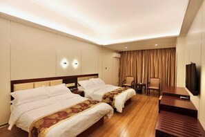 A hotel room with two beds, a desk, a chair, and a TV.