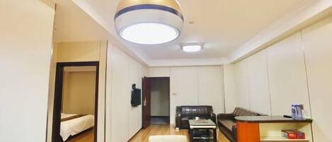 Un espacio habitable compacto con cama, sofá, mesa de centro, escritorio y lámpara colgante.